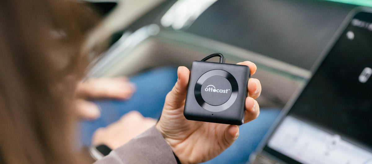 Person holding Ottocast wireless CarPlay adapter device for smart in-car connectivity and media streaming