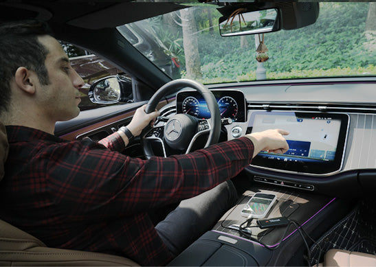 Driver using Ottocast wireless CarPlay adapter in Mercedes-Benz with large touchscreen infotainment system